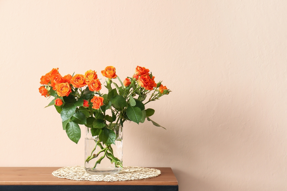 orange roses in a glass vase kept on a table