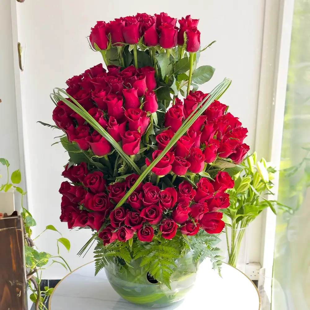 4-step arrangement of 100 roses in a glass vase