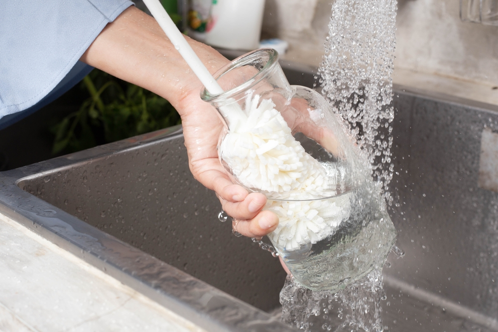 a lady washing a glass bottle with a brush